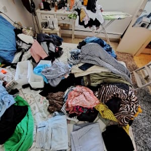 בגדים מקופלים ומסודרים על מיטה בחדר שינה