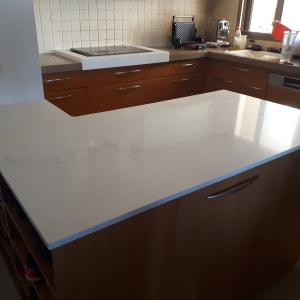 משטח שיש לבן במטבח מודרני עם ארונות עץ