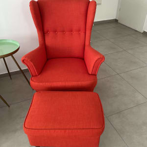 כורסה אדומה עם הדום על רצפת אריחים אפורה