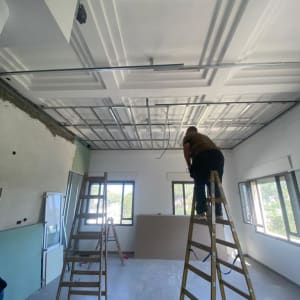 אדם על סולם מתקין תקרה אקוסטית בחדר