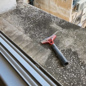 מגרדת אדומה על אדן חלון מלוכלך