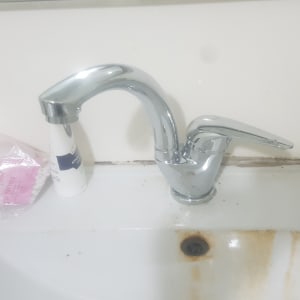 ברז כרום עם כתמי חלודה בכיור לבן