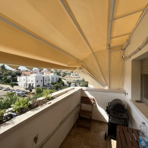 סוכך צהוב נמתח מעל מרפסת עם צמחייה