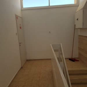 מטאטא ומגב ליד קיר לבן במסדרון