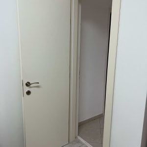 דלת לבנה פתוחה עם ידית מתכת על רצפת אריחים