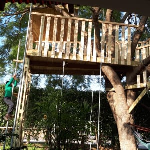 בית עץ מעץ עם סולם וחבלים בגינה