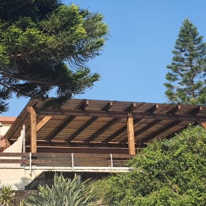 פרגולה מעץ עם קורות עץ על גג בניין