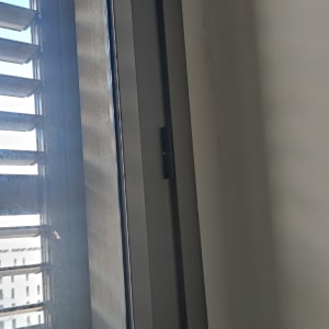 תריסים אפורים על חלון זכוכית עם מסגרת מתכת