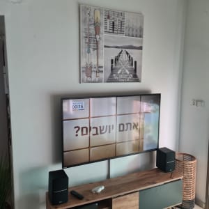 טלוויזיה על קיר עם רמקולים ושלט על מדף