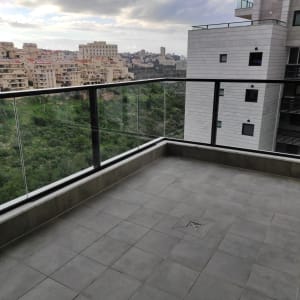 מרפסת עם רצפה נקייה ומעקה זכוכית