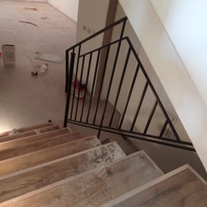 מעקה מתכת שחור על מדרגות עץ בבנייה