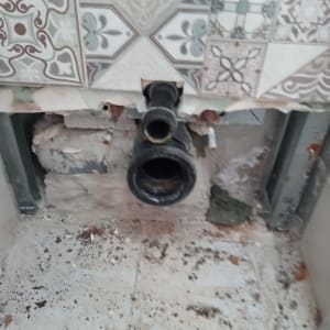 צינור ביוב חשוף בקיר עם אריחים שבורים