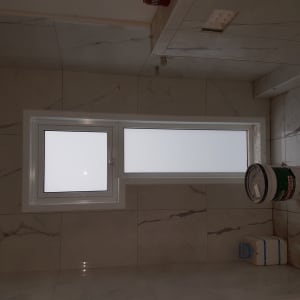 חלון אלומיניום עם זכוכית חלבית על קיר שיש