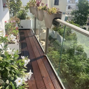 עציצים תלויים על מעקה זכוכית במרפסת עץ