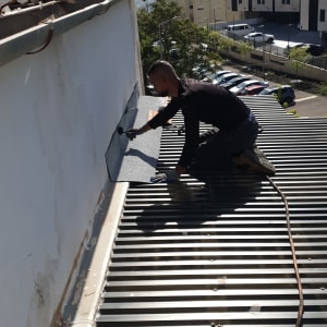 אדם מתקין יריעת איטום על גג מתכת