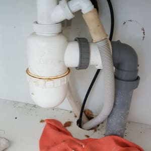 צנרת פלסטיק מתחת לכיור עם מגבת אדומה