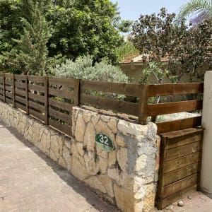 גדר עץ חומה על קיר אבן בגינה
