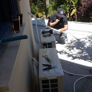 טכנאי מתקין מזגן עם כלים על הגג