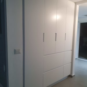 ארון לבן עם דלתות ומגירות בחדר מואר