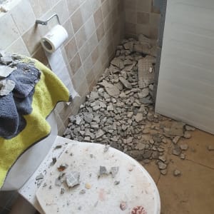 שברי בטון על רצפה ואסלה בחדר אמבטיה