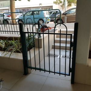 שער מתכת ירוק עם סורגים, ליד מדרגות