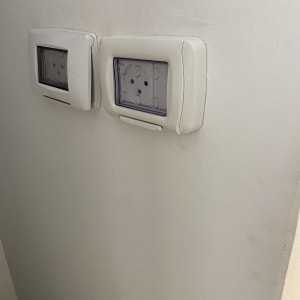 שני שקעים חשמליים עם כיסויים שקופים על קיר לבן