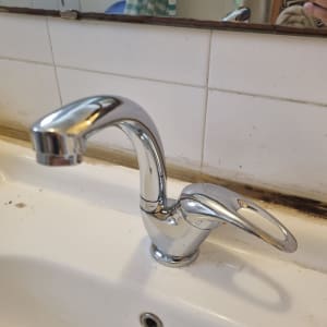 ברז כרום מותקן על כיור לבן עם כתמים