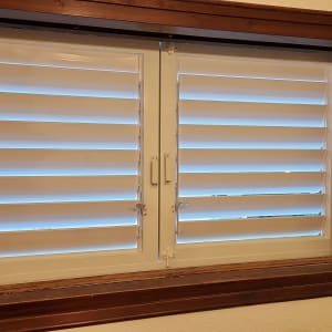 תריסי אלומיניום לבנים בחלון עץ