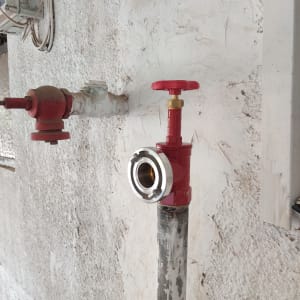 שסתום אדום על צינור מתכת בקיר חיצוני