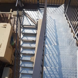 מדרגות מתכת עם מעקה ברזל בצבע כהה