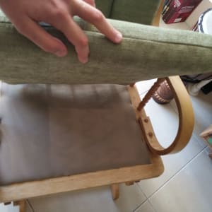 יד מחזיקה כרית ירוקה על כיסא עץ