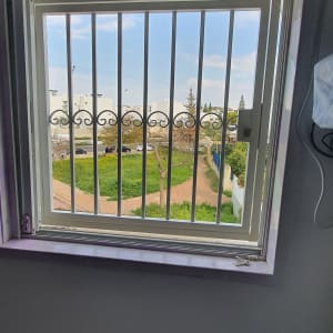 חלון עם סורגים מתכתיים ועיטורים מעוגלים