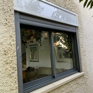 תריסים אפורים סגורים על חלון קיר חיצוני