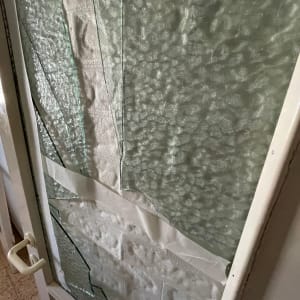 זכוכית שבורה עם קלטת לבנה על דלת