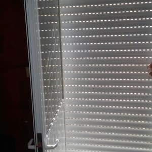 תריסים לבנים עם חריצים לאור על דלת זכוכית