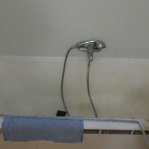 אמבטיה עם ברז ומגבת תלויה על הקצה