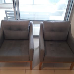 שני כורסאות אפורות עם רגלי עץ על רצפה בהירה