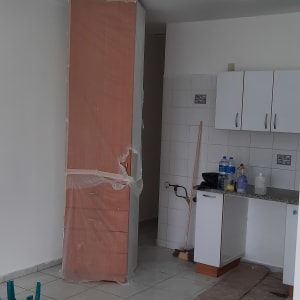 חדר עם ארון מכוסה בניילון, מטאטא וקרטון על הרצפה