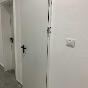 דלתות לבנות עם ידיות שחורות וצירים מתכתיים