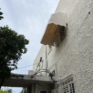 סוכך בד בהיר מעל חלון קיר חיצוני