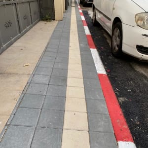 מדרכה מרוצפת חדשה עם אבנים אפורות ובז