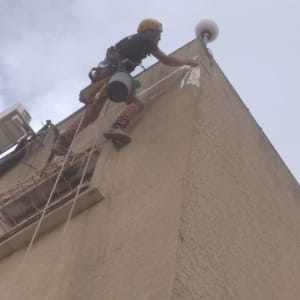 אדם עם קסדה אוטם קיר חיצוני של בניין