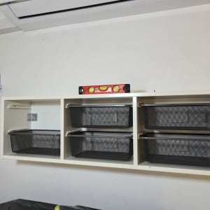 מדף עם סלסלות שחורות ומפלס בנאים אדום