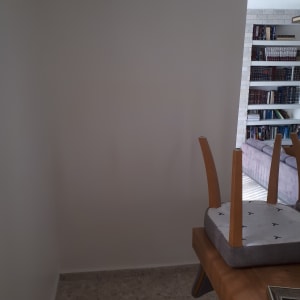 קיר צבוע בלבן עם שולחן עץ וכיסא הפוך