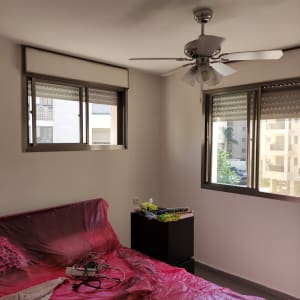 חדר עם מיטה מכוסה בניילון אדום, צבעים על שידה