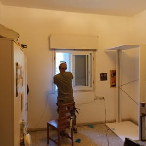 אדם מתקין חלון אלומיניום בחדר