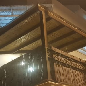 פרגולה מעץ עם גג קש על מרפסת