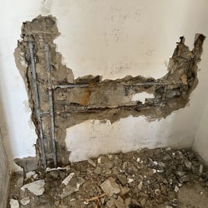 קיר שבור עם צינורות חשופים ועבודת אינסטלציה