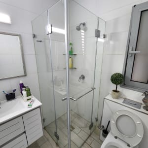 מקלחון זכוכית עם מדפים ומוצרים