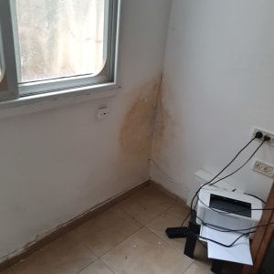 קיר עם כתמי רטיבות ליד חלון